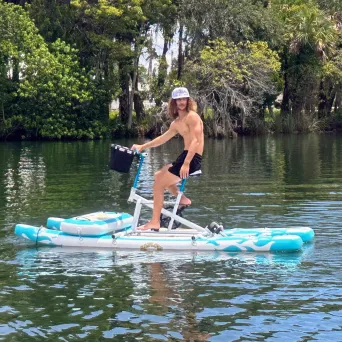 Person on a pedal boat in a lake surrounded by trees.